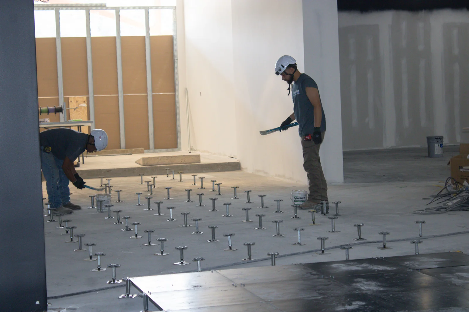 Installers positioning raised floor pedestals during construction