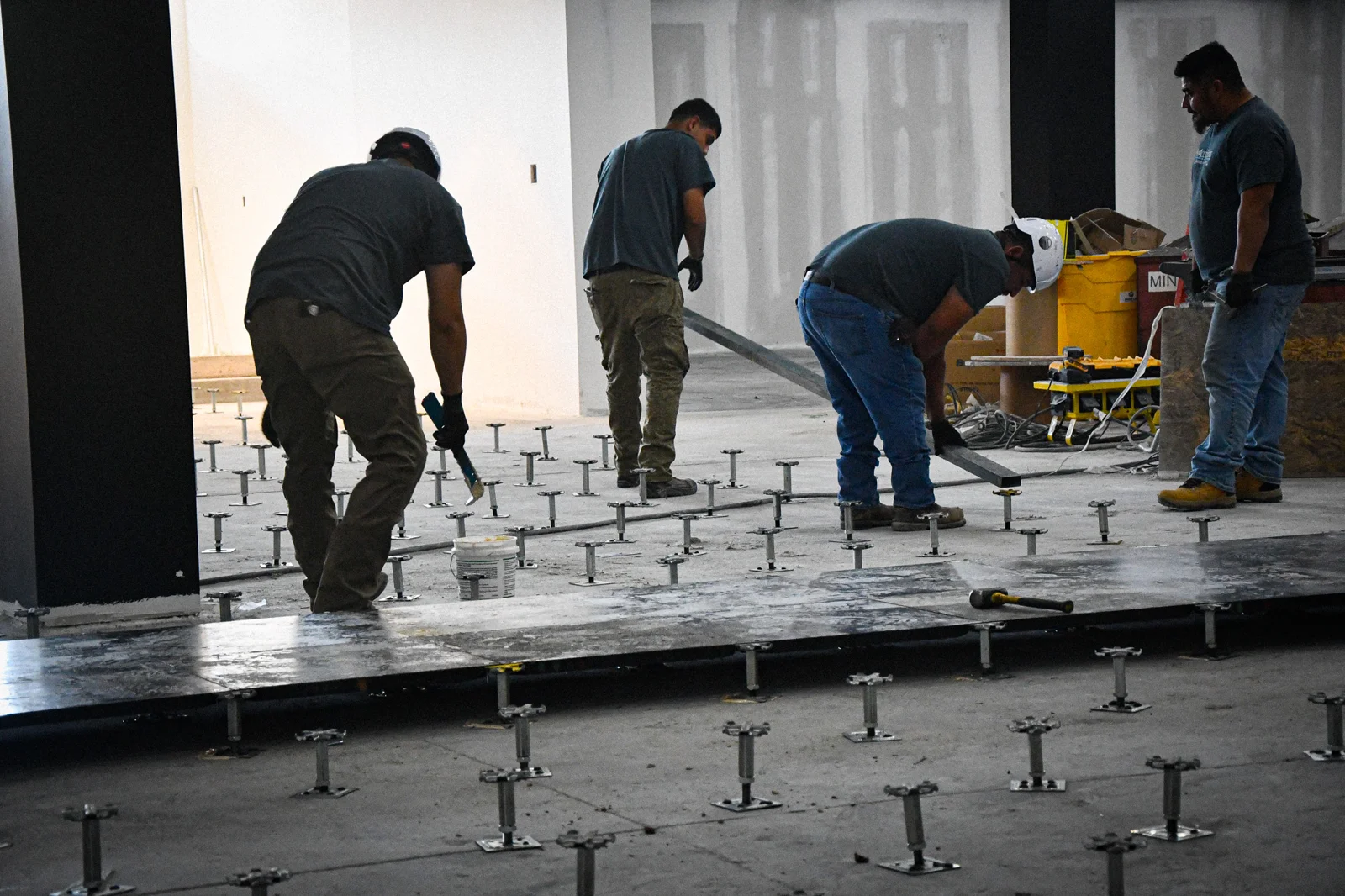 Crew installing raised flooring among exposed pedestals at The Mint Cumberland