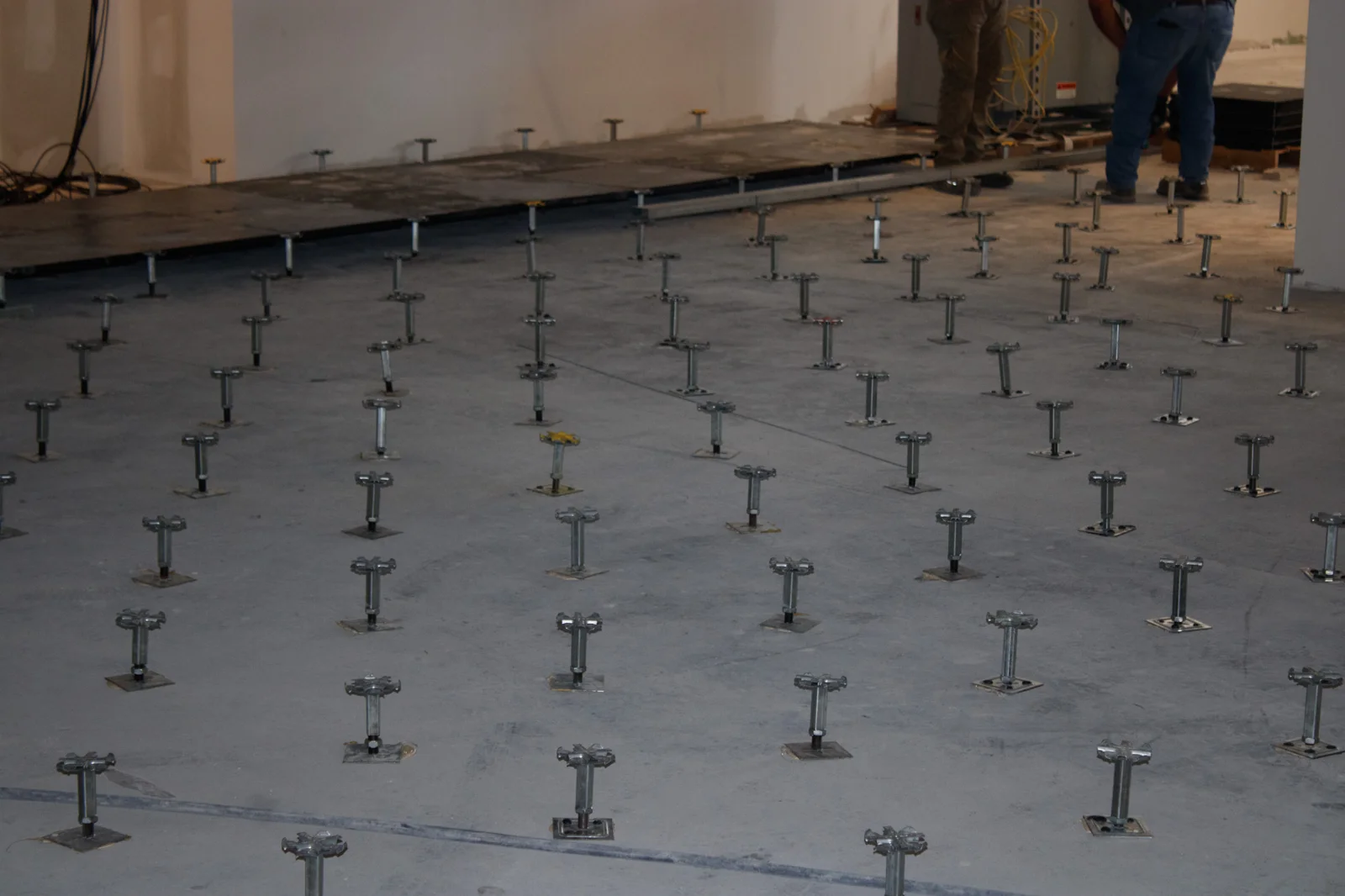 Raised access floor pedestals laid out beside installed panels at The Mint Cumberland