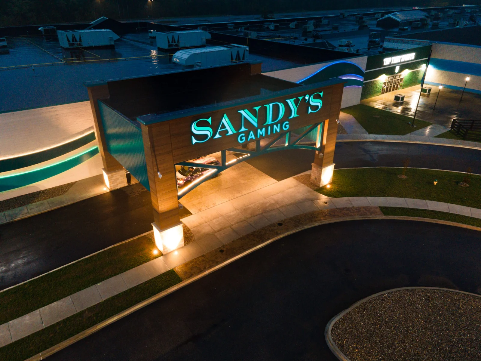 Aerial view of Sandy’s Racing & Gaming entrance illuminated at night